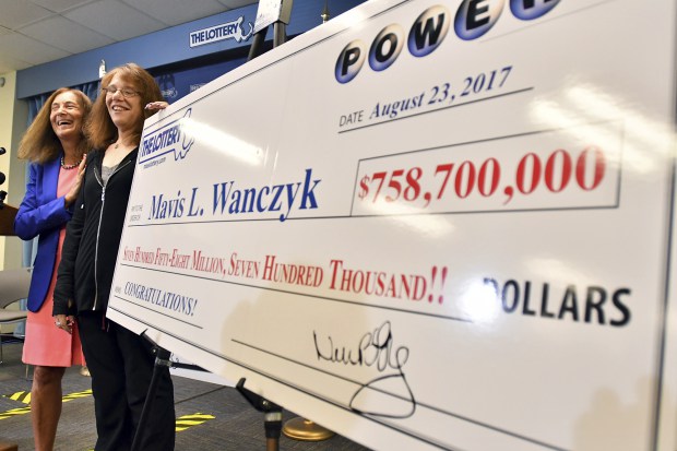 Mavis Wanczyk, of Chicopee, Mass., stands by a poster of her winnings during a news conference where she claimed the $758.7 million Powerball prize at Massachusetts State Lottery headquarters, Thursday, Aug. 24, 2017, in Braintree, Mass. Officials said it is the largest single-ticket Powerball prize in U.S. history. At left is state treasurer Deb Goldberg. (AP Photo/Steven Senne)